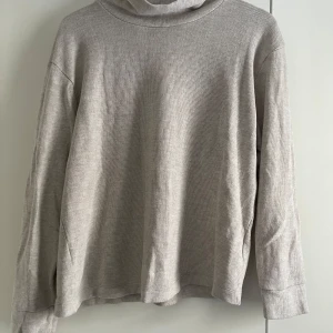 Beige ribbad polotröja - Säljer en stilren beige polotröja med ribbad struktur. Tröjan har långa ärmar och en bekväm passform, perfekt för kyligare dagar. Ett mångsidigt plagg som passar till det mesta i garderoben.