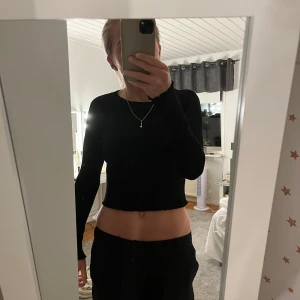 Svart croppad tröja - Säljer en stilren svart croppad långärmad topp. Perfekt för en casual look eller att klä upp med accessoarer. Toppen är i bra skick och passar till både vardag och fest. Skön och enkel att matcha med olika outfits!