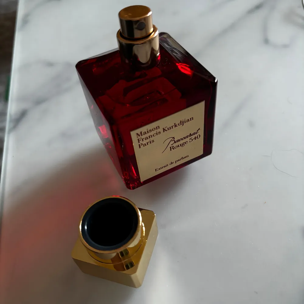 Säljer en parfym av Maison Francis Kurkdjian, Baccarat Rouge 540 Extrait de Parfum. Flaskan är i en elegant röd färg med en guldig kork. Innehåller 70 ml av denna exklusiva doft. Perfekt för den som vill ha något unikt och sofistikerat. Passa på att köpa denna ikoniska doft!. Parfym.