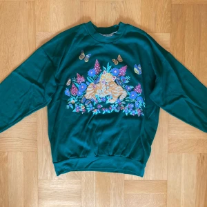 Mörkgrön sweatshirt med kattryck - Grön tjocktröja med katter på. Tröjan är i gott begagnat skick. Den har bara varit använd fåtal gånger av mig, efter att jag köpte den på Beyond Retro. Står ingen storlek men skulle uppskatta ca S-M. Klicka gärna på köp nu och meddela för eventuella frågor. :)