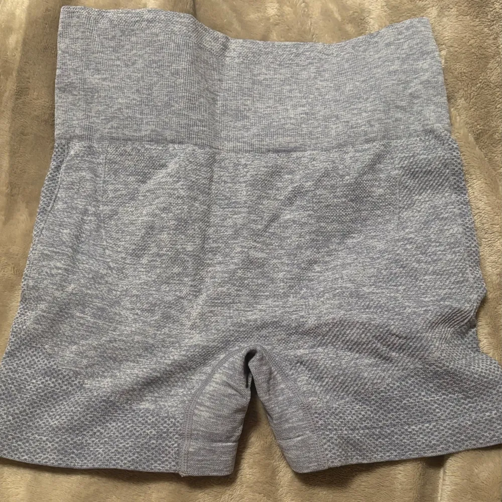 Säljer ett par grå träningsshorts i mycket bra skick. De är högmidjade och har en scrunch-detalj bak som ger en snygg passform. Perfekta för gymmet eller yoga! Materialet är stretchigt och bekvämt. Passar till S med.. Shorts.