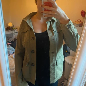 Grön jeansjacka - Säljer en snygg olivgrön ”jeans”jacka från Pernilla Wahlgrens kollektion med Ullared i storlek XS. Jackan har en klassisk design med knappar framtill och praktiska fickor. Aldrig använd ❤️
