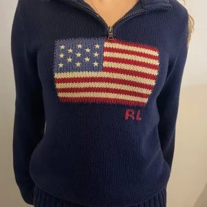 Mörkblå Polo Ralph Lauren stickad tröja - Säljer en snygg trendig mörkblå stickad tröja från Ralph Lauren med ett coolt amerikanskt flaggmönster på framsidan. Tröjan har en dragkedja vid halsen och långa ärmar. Perfekt för höst och vinter! Storlek 14-16 år, passar S! Köpte för 2500 kr 💗