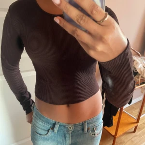 Brun ribbad topp från H&M - Säljer en brun ribbad topp från H&M Divided. Den är croppad och har långa ärmar.