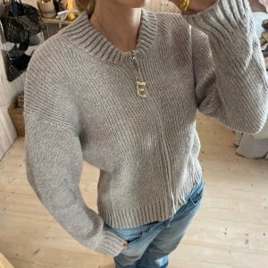 Beige stickad kofta med dragkedja - Säljer en supermysig beige stickad kofta med dragkedja framtill. Perfekt för kyliga dagar och passar till allt! Den har en ribbad struktur och långa ärmar. Perfekt för höst och vinter.💕💕