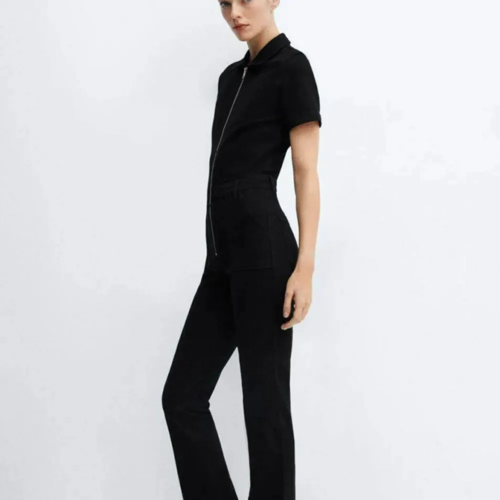 Snygg och stilren svart jumpsuit med korta ärmar och dragkedja framtill. Perfekt för en chic och minimalistisk look. Passar både till vardags och festliga tillfällen. Enkel att styla med accessoarer för en personlig touch. Använd endast 1 gång säljer då den ej kommer till användning💗. Övrigt.