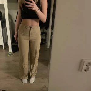 Beigea kostymbyxor med hög midja - Säljer ett par snygga beige byxor med hög midja. De har en straight passform med en knapp på ena bakfickan. Perfekta för både vardag och fest!  De är från Bershka i storlek 36 och nypriset låg på 399 medan jag säljer för 199kr. Använda 1-2 gånger och säljer då jag inte får användning av de längre.