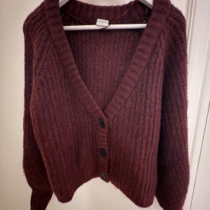 Vinröd stickad kofta  - Mysig vinröd stickad kofta med stora knappar framtill. Jättefin nu till hösten! 
