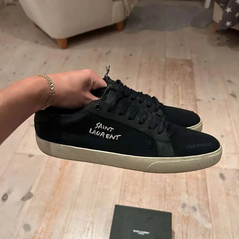 Säljer ett par snygga svarta sneakers från Saint Laurent i mycket bra skick. De har en stilren design med vit sula och Saint Laurent-logga på sidan. Perfekta för både vardag och fest! boxen medföljer.. Skor.