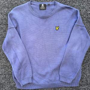 Säljer en snygg blå stickad tröja från Lyle & Scott i storlek M. Tröjan har en klassisk rund hals och ett gult broderat emblem på bröstet. Perfekt för både höst och vinter, och den är i mycket bra skick. Passar till både vardag och fest!