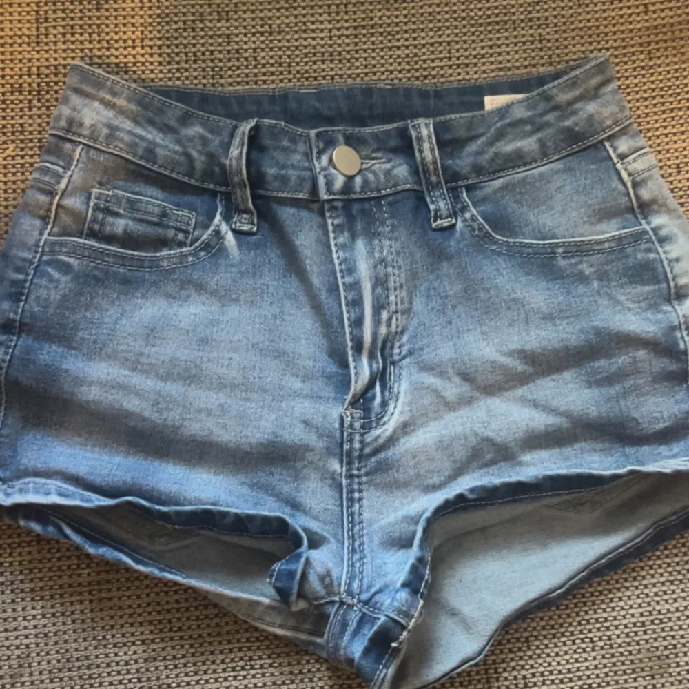 Snygga jeansshorts i blått med hög midja och coola broderade detaljer på bakfickorna. De har en knapp och dragkedja framtill och är i bra skick. Passar perfekt till en avslappnad stil. Köpt från SHEIN men används inte. Shorts.