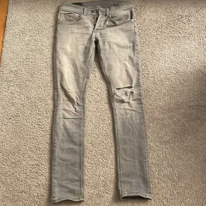 Dondup George - Säljer ett par grå slim jeans ifrån Dondup med modell George i storlek 28. De är i skick 9/10 och nypris är 2500-3000kr. De har en schysst reva på ena benet. Beninnerlängd 76 cm och midjemått 36 cm. Passar dig som är runt 170-172 cm lång. Hör av dig ifall du har några frågor!