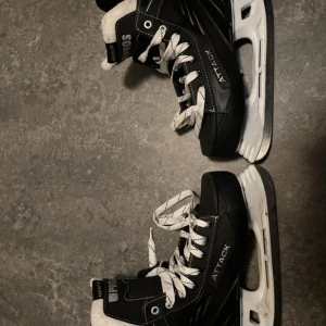 Attack skridskor, 2 Jofa och en hockeyhjälm - Säljer en vit hockeyhjälm från Reebok med svart galler. Hjälmen är i bra skick och passar perfekt för både träning och match. Justerbar för att sitta bekvämt och säkert. Perfekt för vintersäsongen! 🏒, säljer även ett par Attack skridskor väldigt bra på isen lite märken men de påverkar inte känslan när man åker, 2 jofa båda är okej skick funkar fortfarande väldigt bra att använda storlek 41 på 4 bilden och storlek 43 på Attack bild 1, bild 3 storlek 42 
