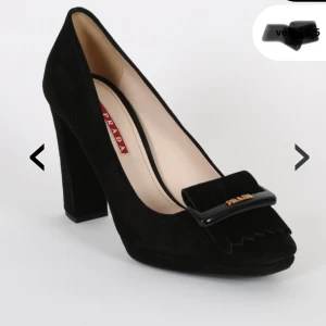Svarta klackskor från Prada - Snygga svarta klackskor från Prada i mocka med fransar och märkets logga framtill. Perfekta för en kväll ute eller en formell tillställning. De har en bekväm blockklack och en stilren design som passar till många olika outfits. Dustbag medföljer. 