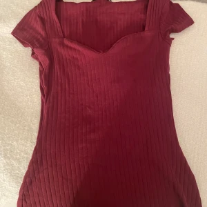 Vinröd ribbad tröja från Anna Field - Säljer en superfin vinröd tröja/blus från Anna Field. Den är ribbad och har en snygg v-ringad design med korta ärmar. Perfekt för både vardag och fest! 💃