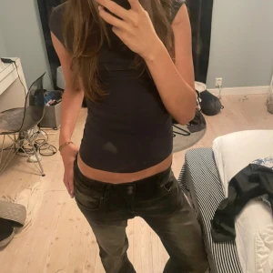 Svart/ grå  ärmlös topp - Säljer en stilren svart ärmlös topp i mycket bra skick. Perfekt för både vardag och fest. Toppen har en tight passform som framhäver figuren och är gjord i ett mjukt och stretchigt material. Passar till alla säsonger och kan enkelt matchas med olika outfits. Storlek xs från Gina Tricot 