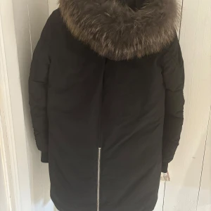 Svart vinterjacka från Rockandblue - Säljer en svart vinterjacka från Rockandblue i mycket bra skick. Parkas liknande jacka.  Jackan har en stor, fluffig pälsfodrad huva och dragkedjor framtill. 