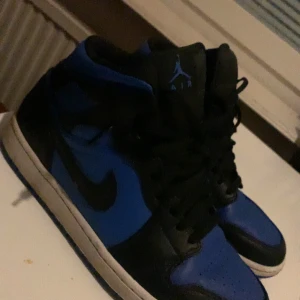 Nike Air Jordans i svart och blått - Säljer ett par snygga Nike Air Jordans i svart och blått. Skorna har en klassisk hög modell med snörning och den ikoniska Air Jordan-loggan. Perfekta för både vardag och fest! De är i bra skick och redo för nya äventyr.