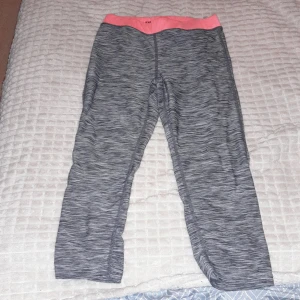 Grå och rosa sportleggings från H&M - Säljer ett par gråmelerade sportleggings från H&M med en snygg rosa midja. Perfekta för träning eller en aktiv dag. De är i bra skick och superbekväma att ha på sig. Passar barn i storlek EUR 134/140.