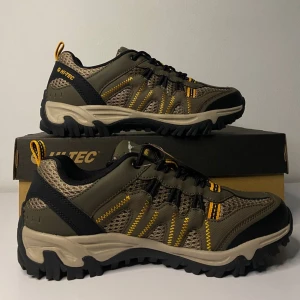 Vegan träningsskor från Hi-Tec - Säljer ett par snygga och robusta träningsskor från Hi-Tec i olivgrön och svart. Skorna har en slitstark sula med bra grepp och är gjorda av veganskt material. De har snörning med gula detaljer som ger en cool kontrast. Perfekta för utomhusaktiviteter och äventyr!