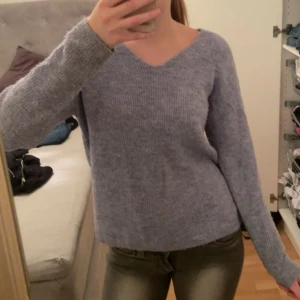  stickad tröja - Mysig ribbad stickad tröja med v-ringning. Perfekt för kyliga dagar och kan stylas både upp och ner. Tröjan har en avslappnad passform och långa ärmar. Kan också bäras lite off shoulder som på andra bilden! Blå-lila i färgen, ärmarna är lite missfärgade och hela tröjan är lite knottrig. 