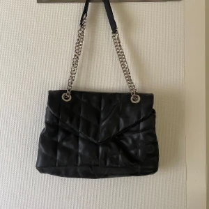 Svart väska med kedja  - Så fin och praktisk väska från Parfois. Kan bäras på olika sätt beroende på hur man har kedjan. Flera fack inuti. Nyskick!!