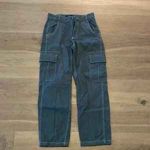 Gröna cargopants - Säljer ett par gröna cargopants i bra skick. De har praktiska fickor på sidorna och en loose passform som är perfekt för en avslappnad stil. Byxorna är gjorda av bomull och har en normal midja. Perfekta för höst och vår!
