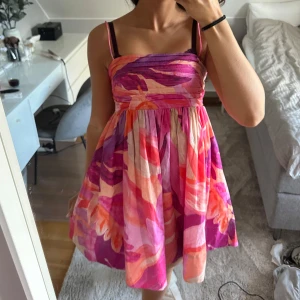 Färgglad sommarklänning  - Säljer en superfin sommarklänning i härliga färger som rosa, orange och lila. Klänningen har smala axelband. Perfekt för sommarens alla fester! Den är i mycket bra skick och har en luftig passform som gör den bekväm att bära hela dagen.