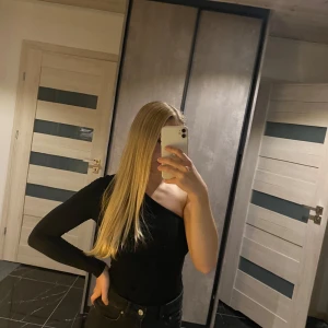 Svart oneshoulder topp - Säljer en stilren svart oneshoulder topp i mycket bra skick. Perfekt för en utekväll eller fest! Toppen har en lång ärm och är gjord i ett mjukt och stretchigt material som sitter snyggt på kroppen.