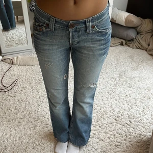 Blå lågmidjade bootcut jeans med slitningar - Säljer dessa snygga blå lågmidjade jeans med coola fickor då de är för små för mig 💓skriv om ni har frågor!