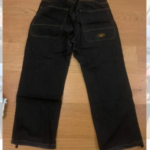 Baggy jeans från District Fortysix - Säljer ett par svart/blåa byxor från District Fortysix med stora bakfickor och en logga på ena fickan. Byxorna har en loose/baggy passform. Byxorna kommer inte till användning längre så har valt att sälja de. De är lite slitna i ljumskarna. Bara att höra av sig vid intresse eller prisförslag :) kan komma överens om pris vid snabb affär :)
