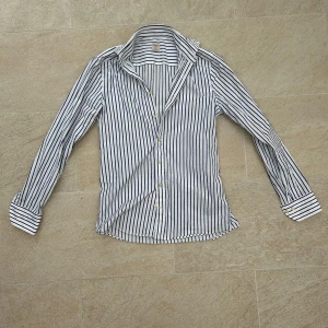 Randig skjorta från Stenströms - Säljer en stilren vit och blå randig skjorta från Stenströms i slim fit. Skjortan har långa ärmar och knappar framtill. Perfekt för en klassisk och elegant look. Passar bra på mig som är 182. Hör av dig vid frågor!