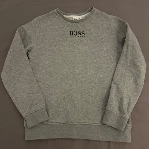 Hugo Boss Tröja Barn - Storlek: Barn 11-13 år XS | A: 46cm | B: 58cm | C: 55cm | D: 42cm | E: 13cm | Grå Hugo Boss tröja som passar bra till barn, tröjan har använts max 5 gånger