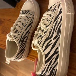 Zebramönstrade sneakers från NA-KD - Snygga sneakers med zebramönster från NA-KD. Skorna har använts fåtal gånger, lite smutsiga men som förmodligen går bort i en tvätt bara! Passar 37 & 38. 