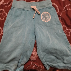 Blå shorts med snörning - Snygga blå shorts med snörning i midjan och ett tryck på ena benet. Perfekta för en avslappnad stil.