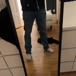 Blå jeans från Nudie - Säljer ett par klassiska blå jeans från Nudie. De har en normal passform och är tillverkade i slitstarkt denim. Perfekta för en avslappnad stil med snygga detaljer på bakfickorna.