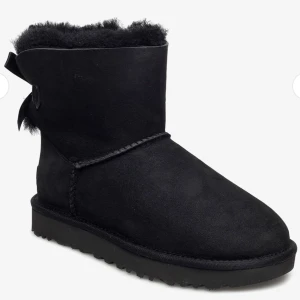 UGG W Mini Bailey Bow II🎀 - Snygga svarta skor från UGG med en rosett baktill. Fick dessa i födelsedagspresent förra året men de har inte kommit till användning. Tyvärr ingen box kvar. Endast använda ett fåtal gånger gånger. Bilder kan självklart skickas vid önskemål 
