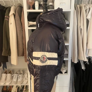 Mörkblå dunjacka från Moncler - Hej!  Jag säljer nu min moncler vinterjacka. Det är ursprungligen en herrjacka, och är i storlek S. Jag köpte den från början av @kaspersheat för 3500kr (second hand), men det jag inte visste då var att den hade en del defekter (gick ej att returnera och framgick ej innan köp). Jag har bifogat bilder på allting. Jag har tagit jackan till både kemtvätt och en sömmerska som har försökt lappa ihop och sy hålen. Hoppas att den kan hitta en ny ägare som använder den! 