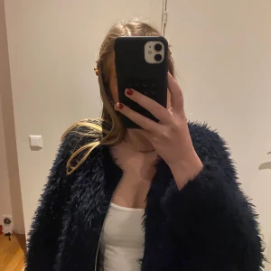 Mörkblå pälsjacka - Snygg mörkblå pälsjacka med dragkedja framtill. Perfekt för att hålla sig varm och stilren under kyligare dagar. Jackan har en normal passform och långa ärmar.