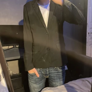 Svart kavaj från Lindex - Snygg svart kavaj från Lindex i storlek 164. Skick 8,5/10. Modellen på första bilden är 167cm lång. Skriv vid minsta fundering!