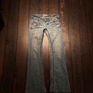 Blå low waist bootcut jeans från Anap Mimpi - Säljer ett par snygga blå low waist bootcut jeans från Anap Mimpi. De har en sliten look med små revor. Dock har de ett hål på baksidan, men man märker inte av det jätte mycket när man har en större tröja över❤️. Dessa jeans sitter tajt 