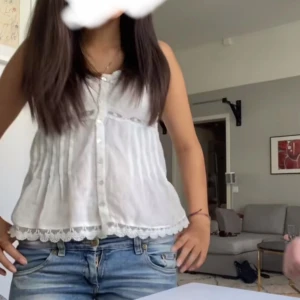 Vit ärmlös blus med spetsdetaljer - Säljer en söt vit ärmlös blus med knappar framtill och spetsdetaljer från Zara. I storlek Xs-s