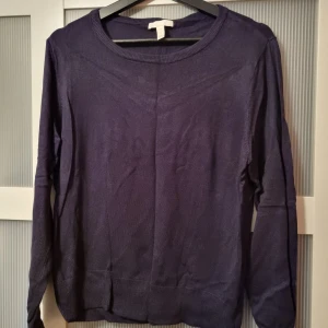Mörkblå stickaf tröja från H&M - Säljer en stilren mörkblå stickad tröja från H&M Basics. Tröjan har en rund halsringning och långa ärmar, perfekt för en avslappnad look. Passar bra till både jeans och kjol.
