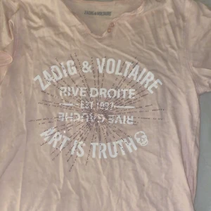 Rosa t-shirt från Zadig & Voltaire - Snygg rosa t-shirt från Zadig & Voltaire med tryck 'Art is Truth' i vitt och glittrande/diamanter detaljer. Perfekt för en avslappnad stil med en touch av glamour.