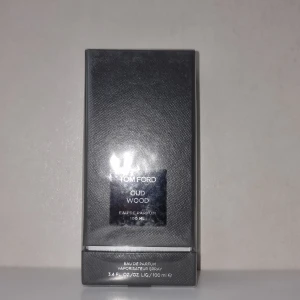 Tom Ford Oud Wood Eau de Parfum - Säljer parfym från Tom Ford, Oud Wood Eau de Parfum, i en elegant mörkgrå förpackning. Flaskan innehåller 100 ml av denna exklusiva doft som är känd för sina rika och träiga noter. Perfekt för den som vill ha en sofistikerad och unik doftupplevelse