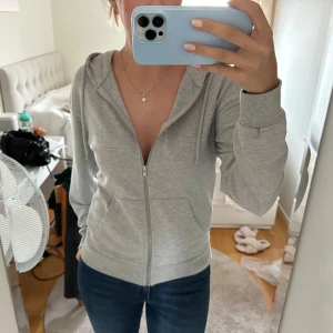 Grå hoodie från Even&Odd - Säljer en supermysig grå zip up från Even&Odd. Den har en dragkedja framtill och en skön huva med snören. Perfekt för en chill dag eller när du vill ha något bekvämt att mysa i. Den är i bra skick och passar till det mesta i garderoben!