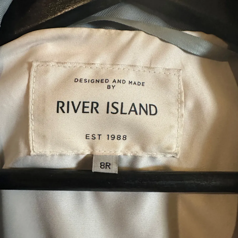 Säljer en snygg ljusblå trenchcoat från River Island. Den har en klassisk design med ett bälte i midjan och långa ärmar. Perfekt för vår och höst när du vill ha en stilren look. Jackan är i bra skick och redo för nya äventyr!. Jackor.