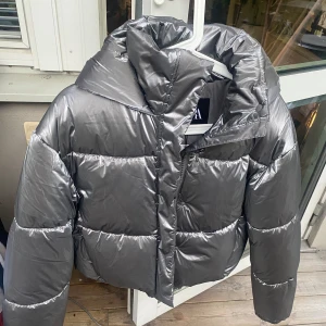 Pufferjacka - Grå metallic lättvikts pufferjacka  i storlek XS. Aldrig använd, alla lappar kvar