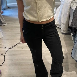 Svarta byxor med knappar - Säljer ett par svarta byxor med hög midja och knappar framtill. De har en tight passform och är perfekta för både vardag och fest. Byxorna är i bra skick och superbekväma att ha på sig.