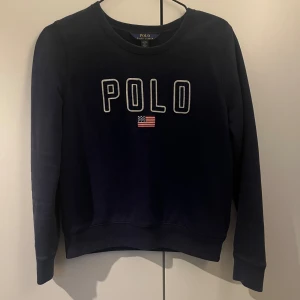 Mörkblå tröja från Polo Ralph Lauren - Tröja från Polo Ralph Lauren i jättefint skick, med insytt tryck på framsidan. Storleken på tröjan är XL (barnstorlek), vilket motsvarar XS i vuxenstorlek. Kan fraktas omgående!